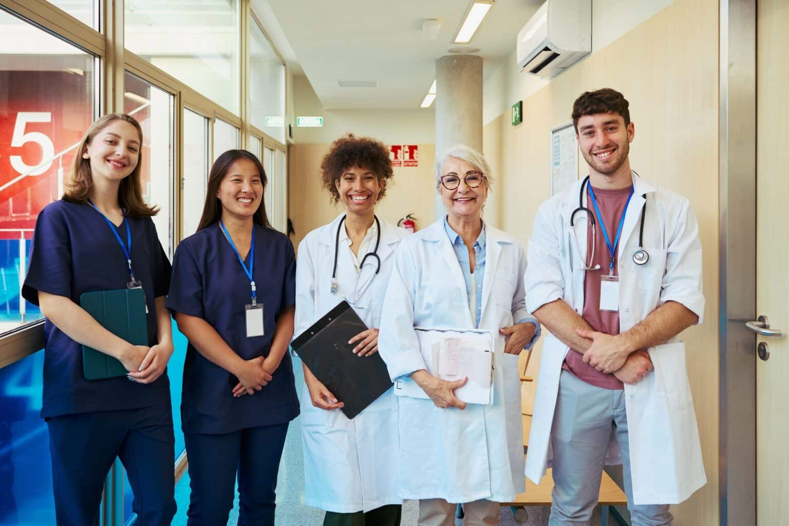 Medical team smiling in hospital corridor: doctors and nurses collaborative healthcare