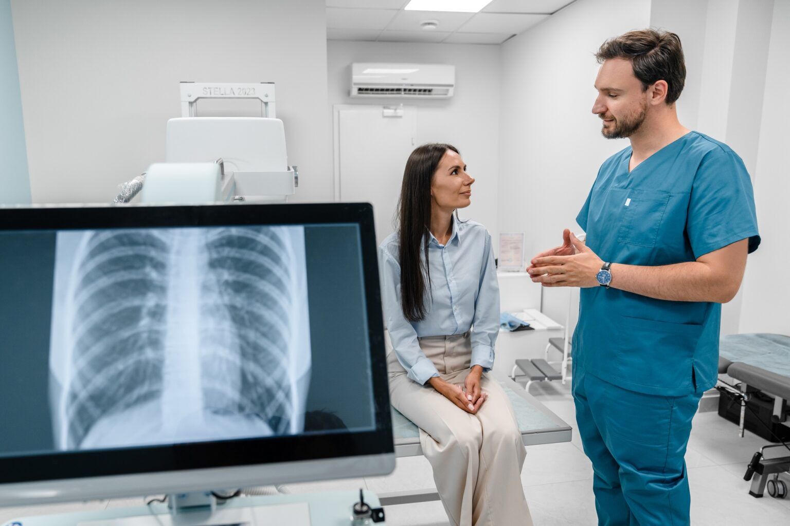 Caucasian young doctor radiologist explaining diagnosis on lung x-ray fluorography to patient
