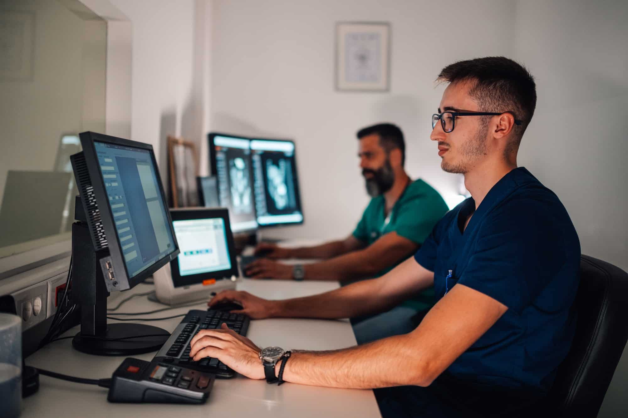 Radiology team reviewing patient scans on computer monitors