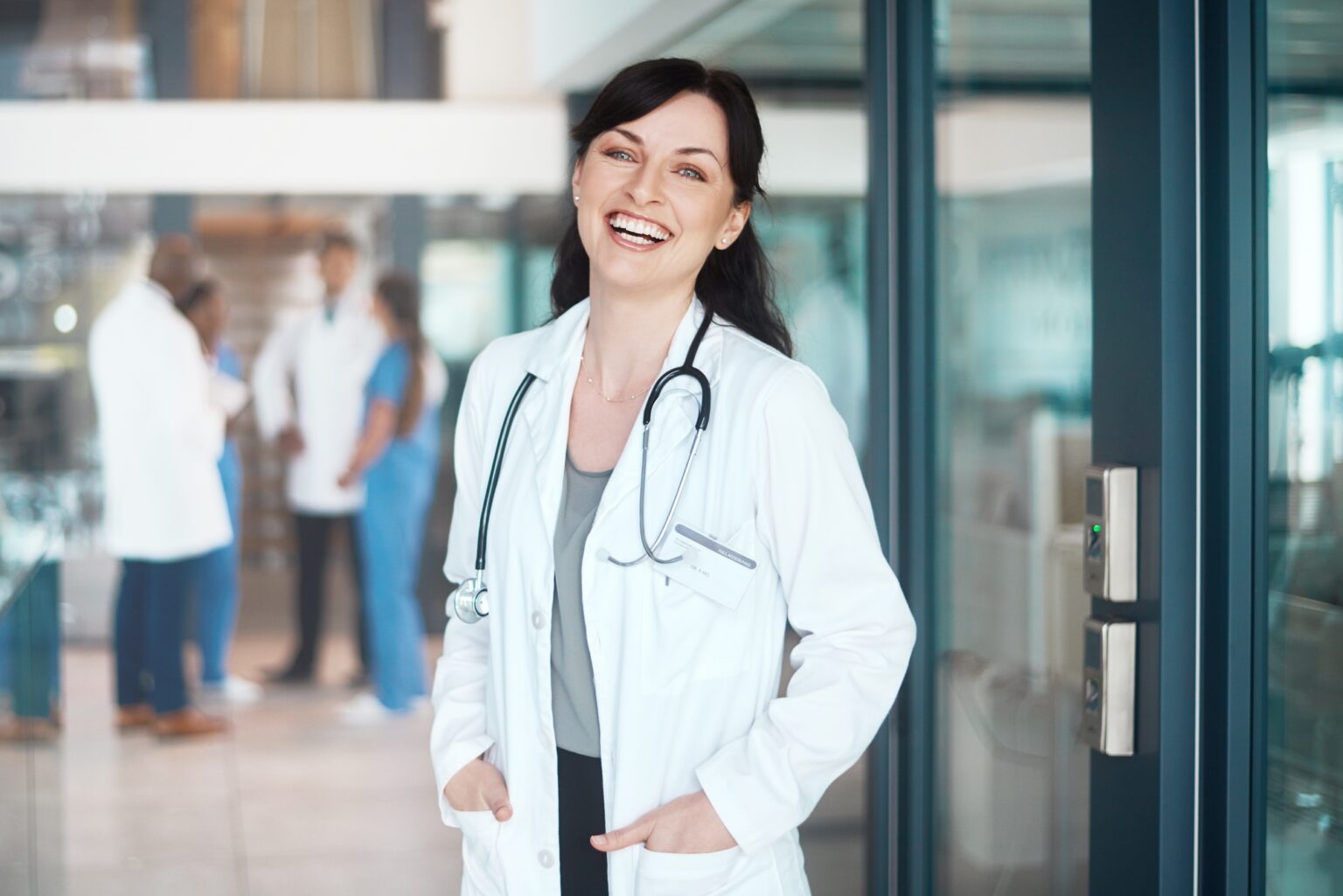 Portrait of a confident doctor working in a hospital with her colleagues in the background