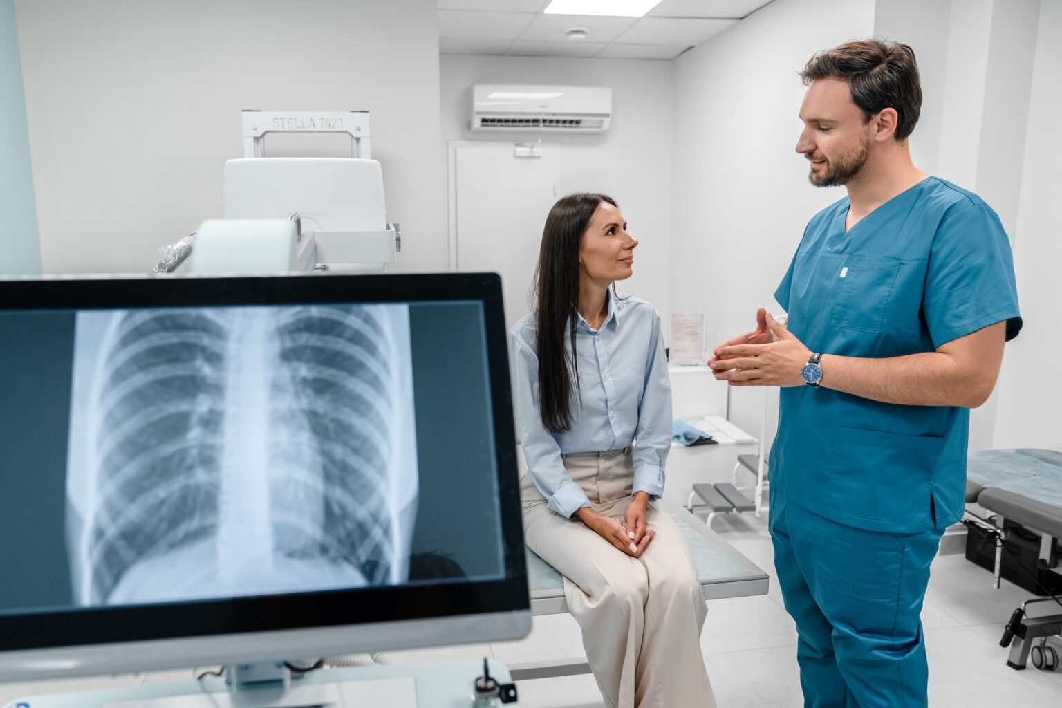 Caucasian young doctor radiologist explaining diagnosis on lung x-ray fluorography to patient